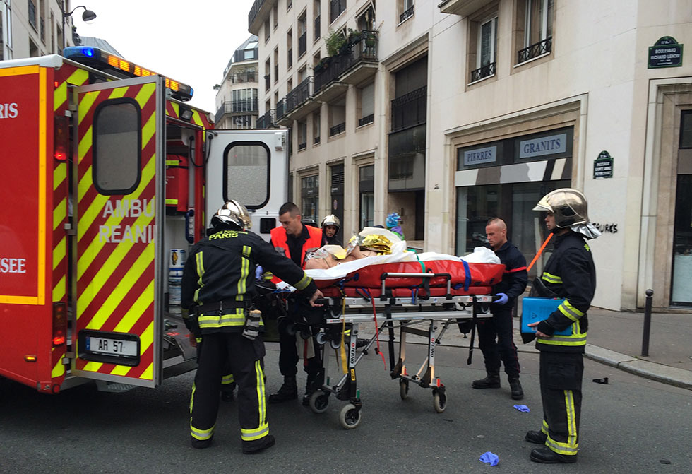 Firefighters carry an injured man on a stretcher in front of the offices of the French satirical newspaper Charlie Hebdo in Paris on January 7, 2015, after armed gunmen stormed the offices leaving at least one dead according to a police source and "six seriously injured" police officers according to City Hall.