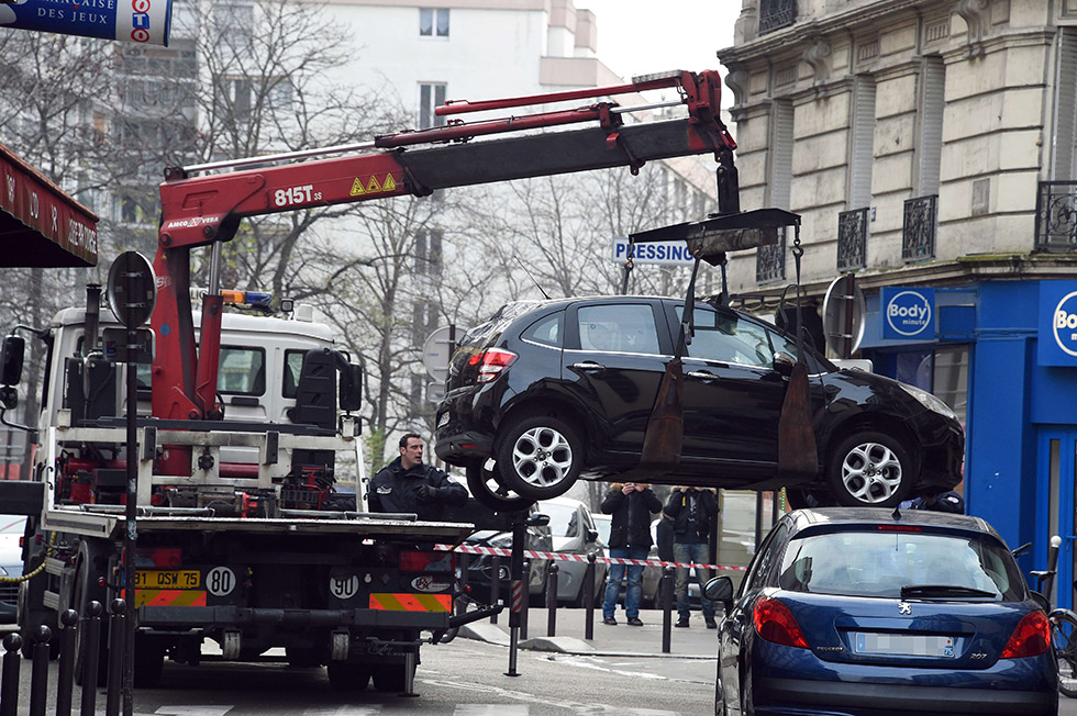 A truck tows the car used by armed gunmen who stormed the Paris offices of satirical newspaper Charlie Hebdo, killing 12 people, on January 7, 2015 in Paris. A source close to the investigation said two men "armed with a Kalashnikov