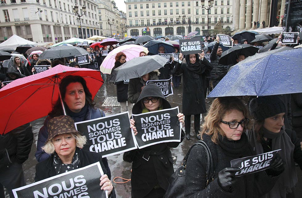 People hold signs reading "Je suis Charlie" (I am Charlie) place de la Bourse in Paris as they observe a minute of silence on January 8, 2015 for the victims of an attack by armed gunmen on the offices of French satirical newspaper Charlie Hebdo in Paris on January 7 which left at least 12 dead and many others injured.