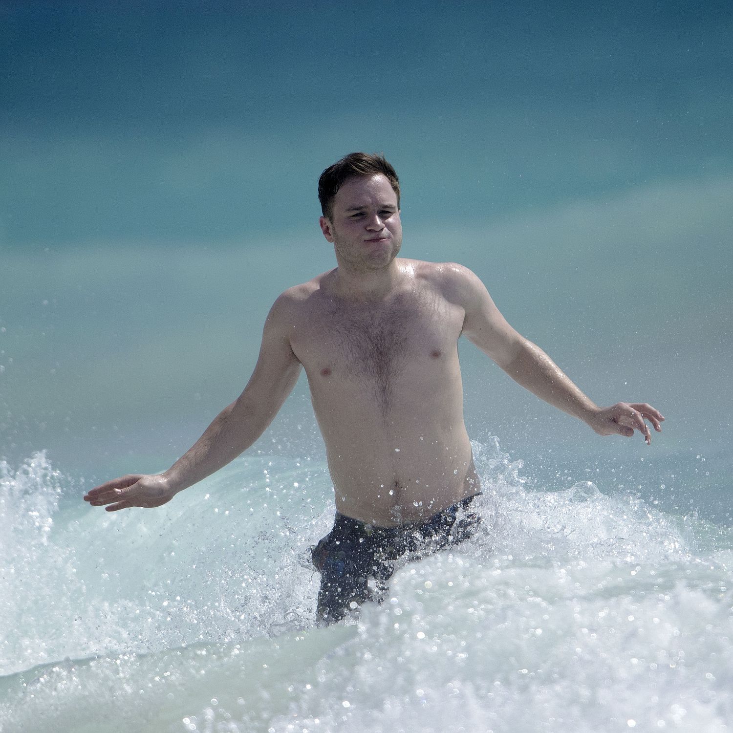 Olly shows his dad bod off on the beach