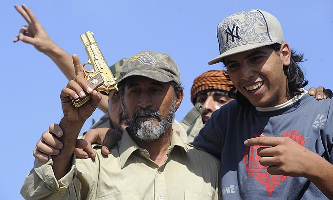 ibyan National Transitional Council (NTC) fighters hold what they claim to be the gold-plated gun of ousted Libyan leader Moamer Kadhafi at the site where the latter was allegedly captured in the coastal Libyan city of Sirte on October 20, 2011.