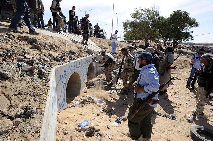 Libyan National Transitional Council (NTC) fighters gather outside large concrete pipes where ousted Libyan leader Moamer Kadhafi was allegedly captured in the coastal Libyan city of Sirte on October 20, 2011. An NTC commander had told AFP that Kadhafi was captured as his hometown Sirte was falling, adding that the ousted strongman was badly wounded