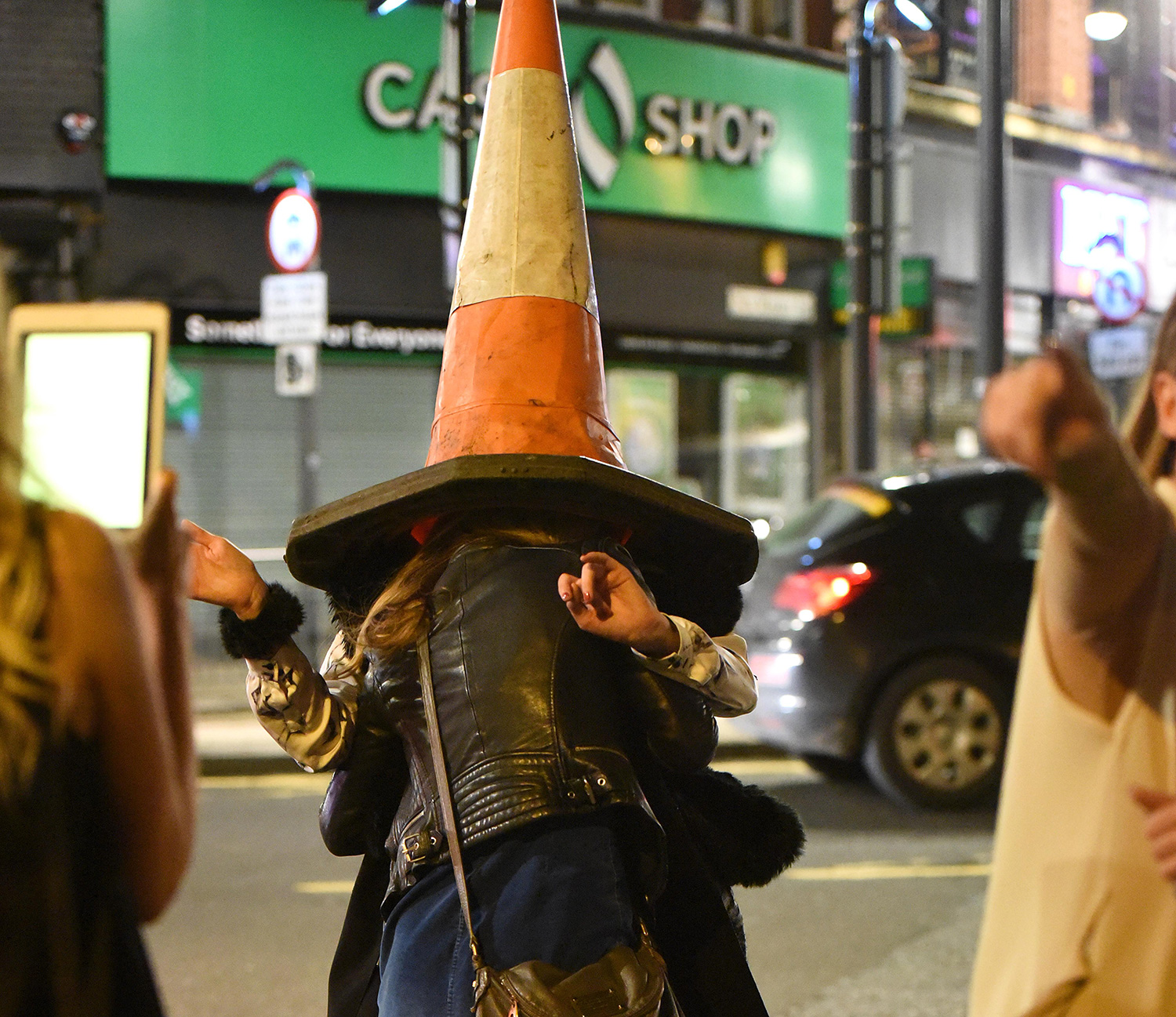 A traffic cone covers the heads of Mad Friday in revellers in Leeds.