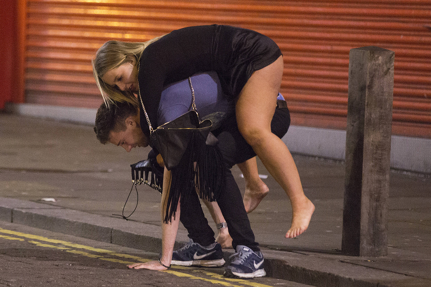 : A male attempts to pick up his female companion so that he can give her a piggyback Re: Mad Friday in Liverpool, England UK. Early hours of Saturday 19 December 2015