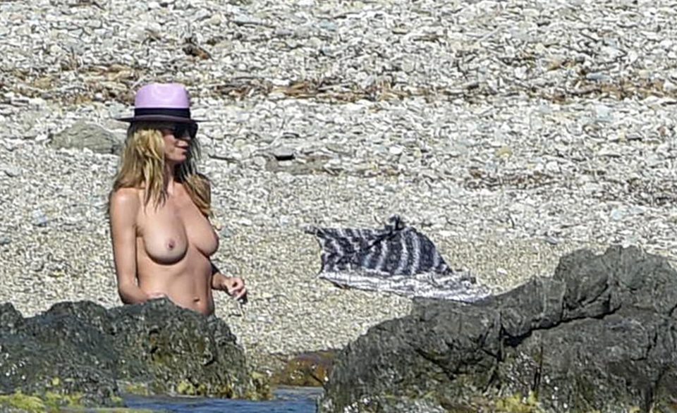 Heidi strips off her dress and bares all as she takes to the sea in nothing but bikini bottoms and a pink hat 