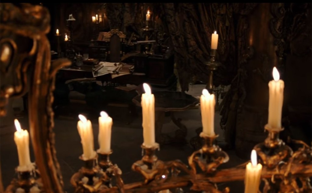 A dark and dusty room is lit by candlelight