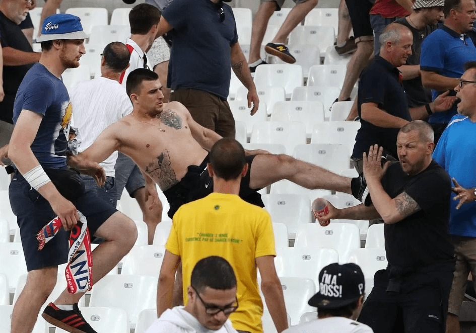  A shirtless thug with distinctive tattoos launches a kick at an England fan