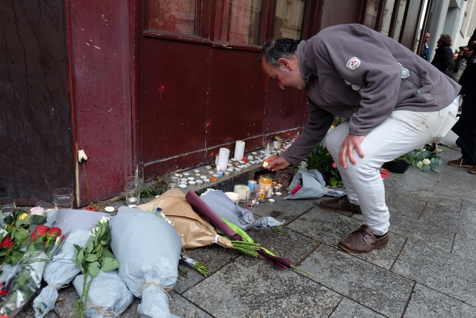  A man lights a candle outside Le Carillon where 15 people were killed by machine gun fire from Islamic State butchers