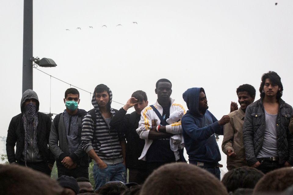  Migrants stand as they wait to board a bus to a new home. The new homes are expected to be across Paris and France