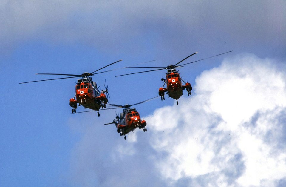  Three distinctive red helicopters fly close to each other against a background of blue sky and white clouds, making an eye-catching picture