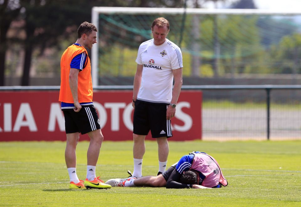 Manager Michael O'Neill check on injured player Kyle Lafferty who later limped out of the training session