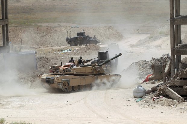 Members of the Iraqi security forces ride in a tank on the outskirts of Fallujah