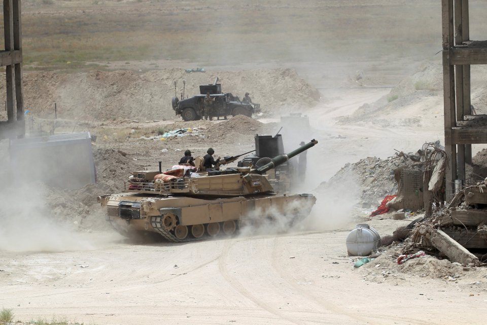  Members of the Iraqi security forces ride in a tank on the outskirts of Fallujah