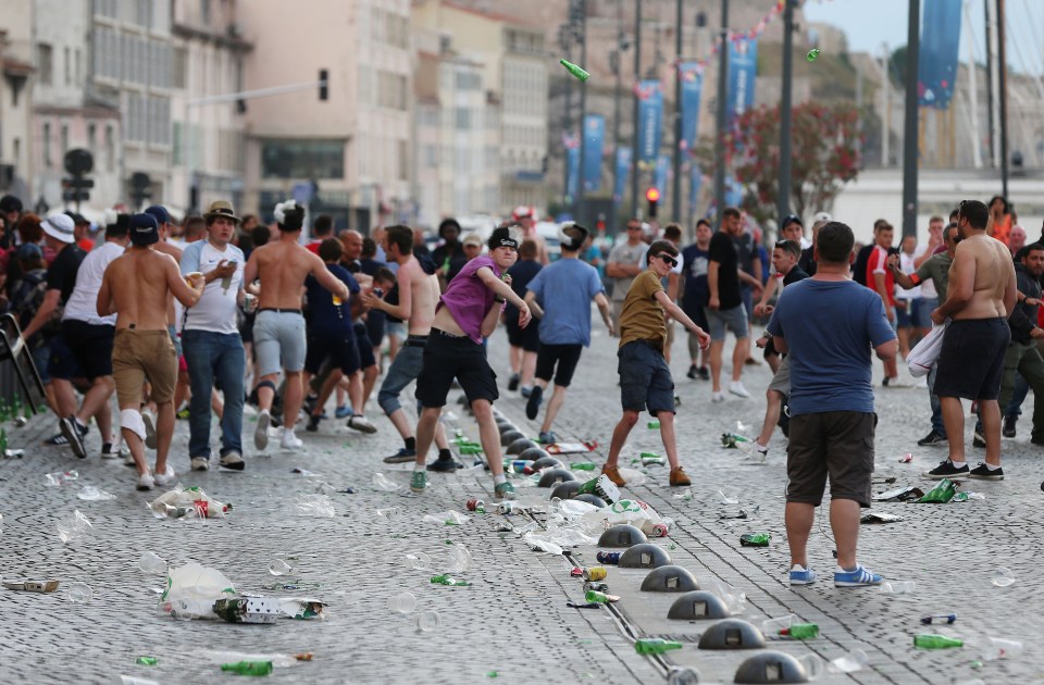  Fans are captured hurling bottles at police during violent clashes...