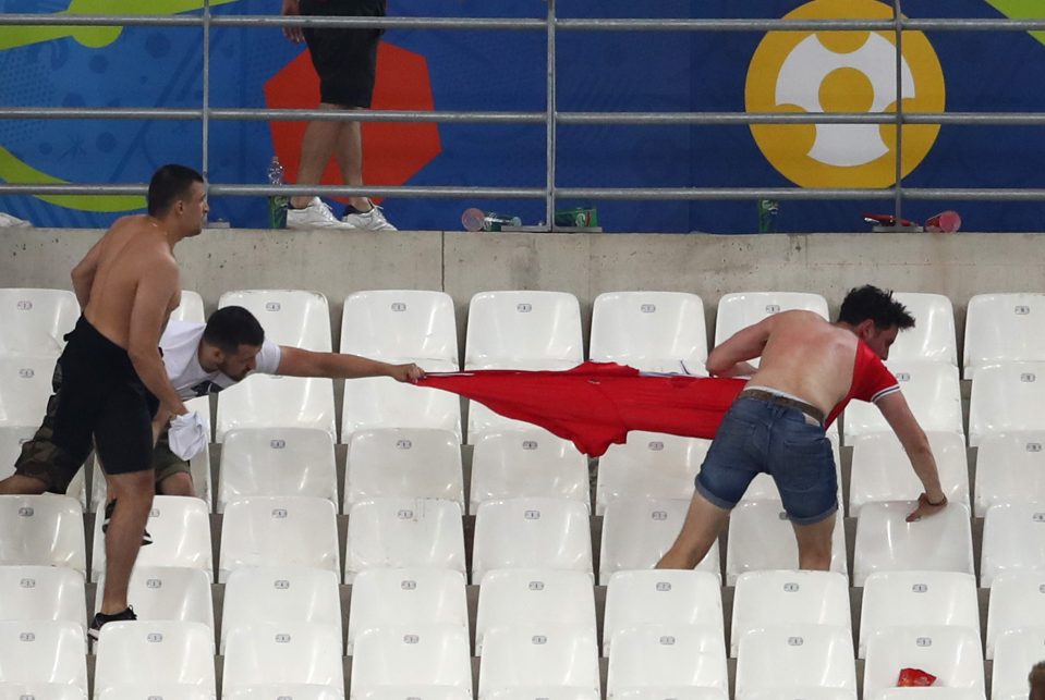  Brutal scenes ... football supporters rip shirt off another fans' back