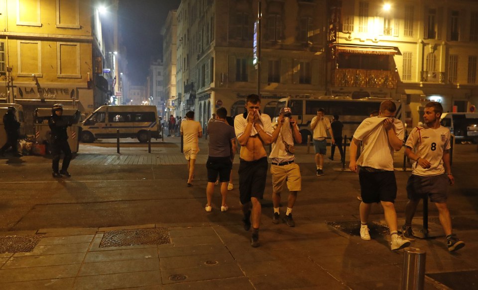 England supporters cover their faces after police fired tear gas following clashes