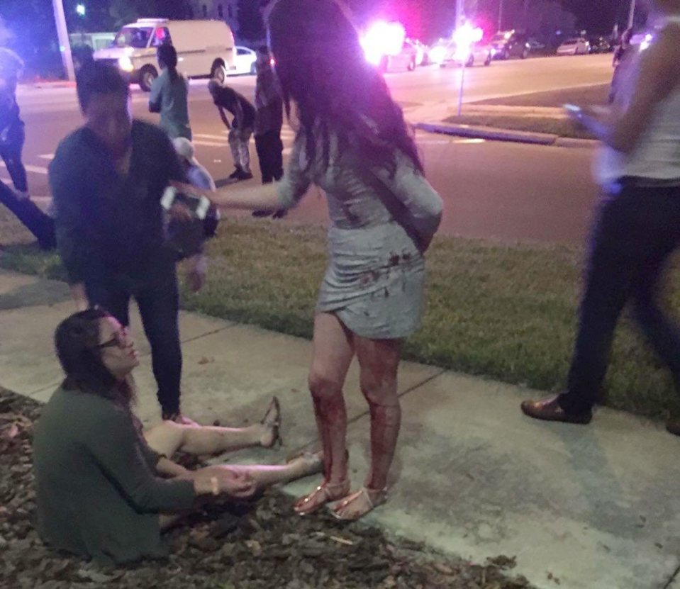 Traumatised clubbers sit on the pavement across the street from the venue