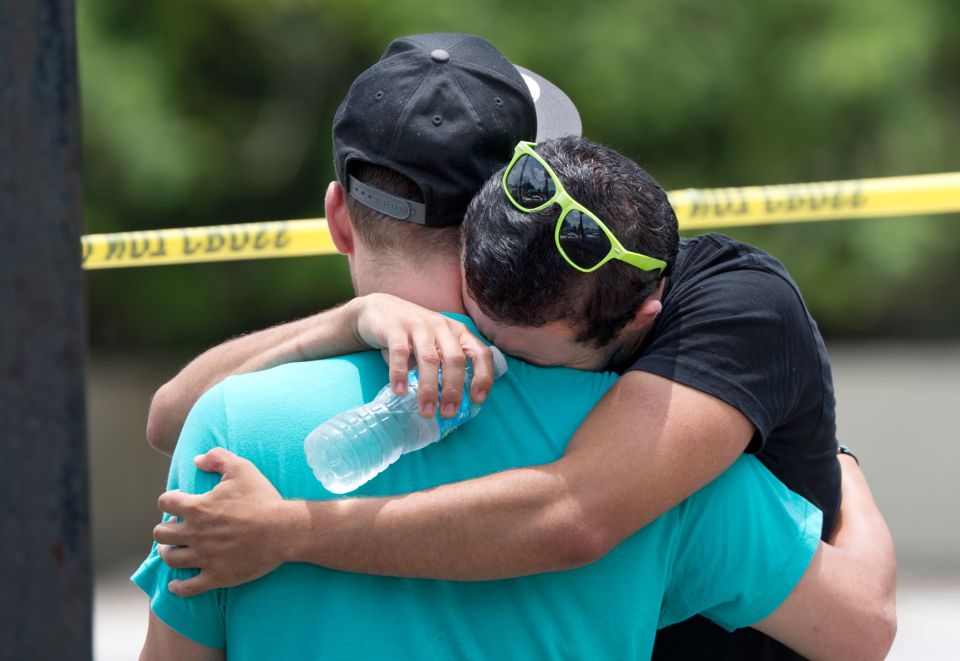 Supported by a friend, a man weeps for v