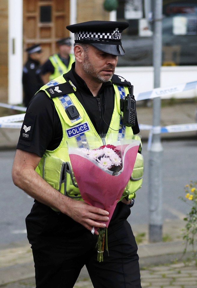  A police officer carries a floral tribute near the scene of the murder of Labour member of Parliament Jo Cox in Birstall near Leeds