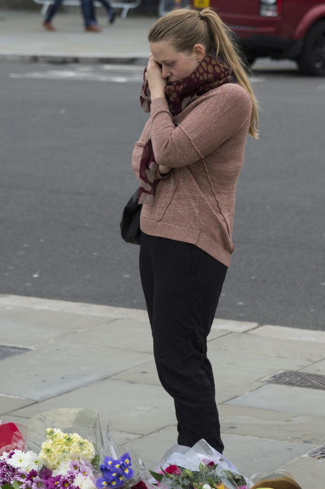  A well wisher wipes away her tears in front of flowers and tributes in Parliament Square in memory of the Labour MP