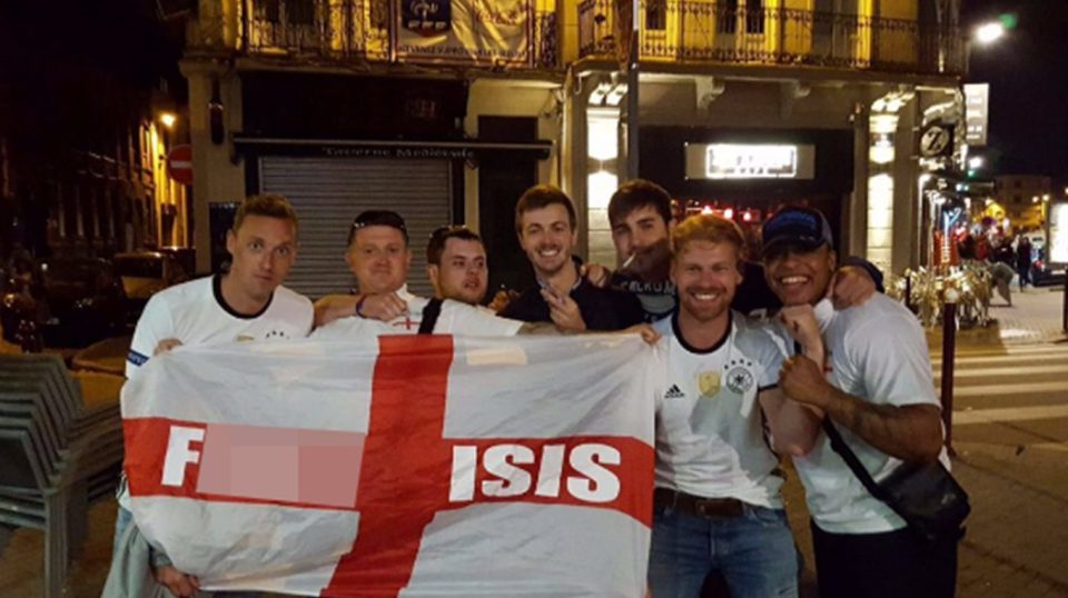  Robinson poses with a group of Germany fans to brandish the same provacative flag