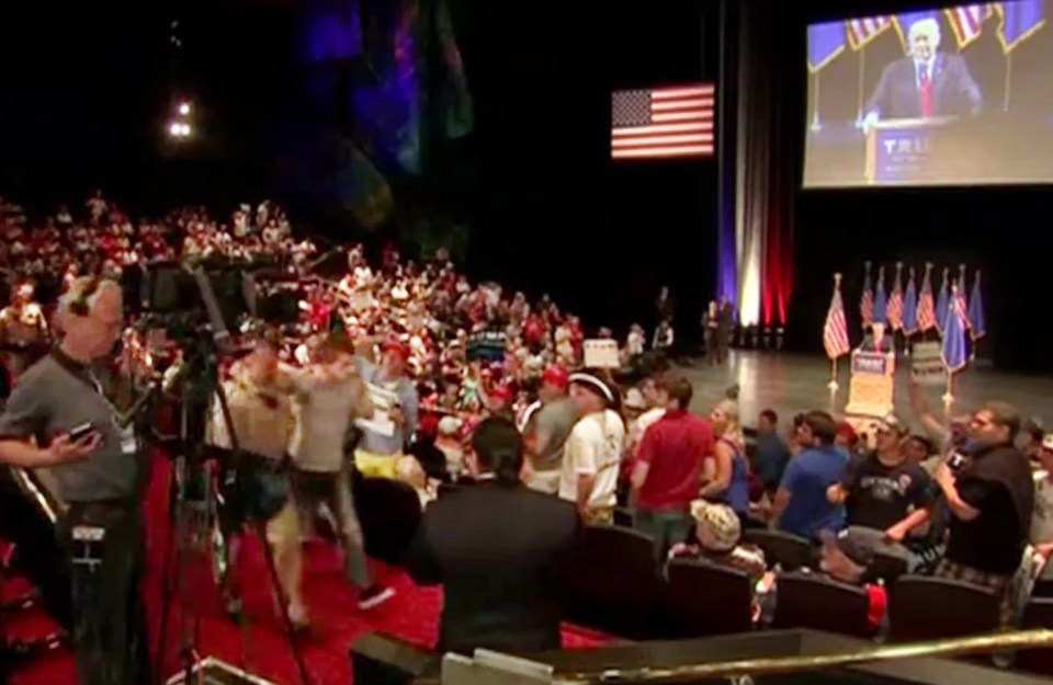 Michael Sanford is escorted away by police after allegedly trying to grab a gun to shoot Trump