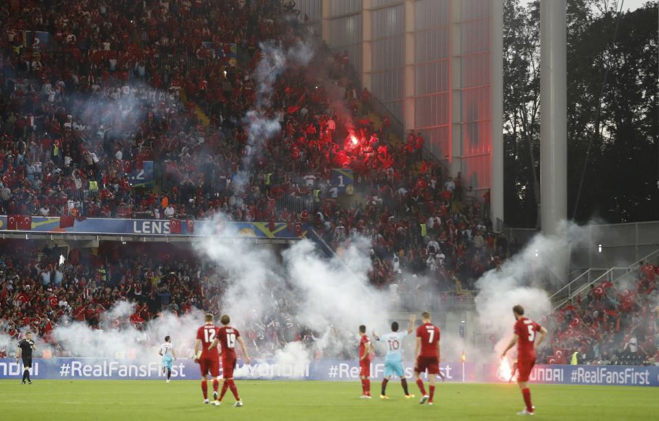  The players wait for the smoke and flares to be cleared in Lens