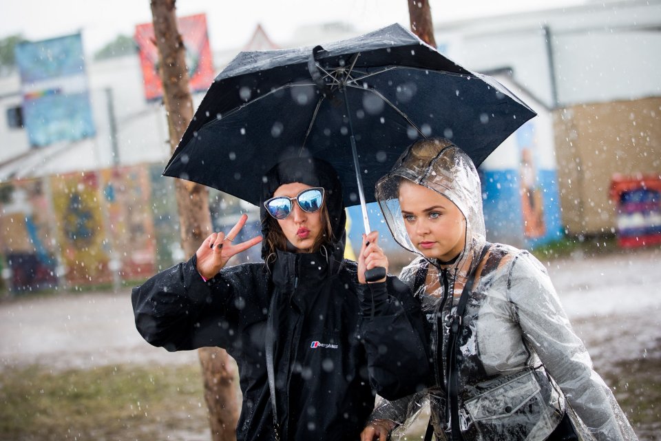 People run for cover during heavy rain in the Hospitality area at Glastonbury Festival, Pilton, Somerset. 24 June 2016. The Glastonbury Festival is a five-day festival of contemporary performing arts that takes place near Pilton, Somerset. In addition to contemporary music, the festival hosts dance, comedy, theatre, circus, cabaret, and other arts