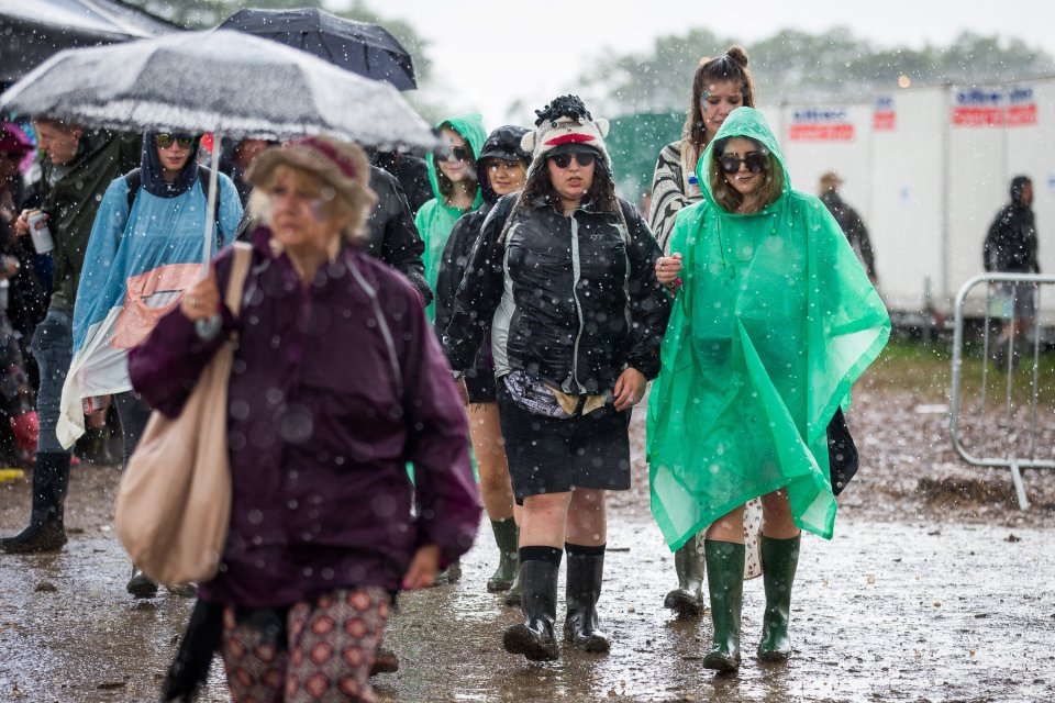 People run for cover during heavy rain in the Hospitality area at Glastonbury Festival, Pilton, Somerset. 24 June 2016. The Glastonbury Festival is a five-day festival of contemporary performing arts that takes place near Pilton, Somerset. In addition to contemporary music, the festival hosts dance, comedy, theatre, circus, cabaret, and other arts