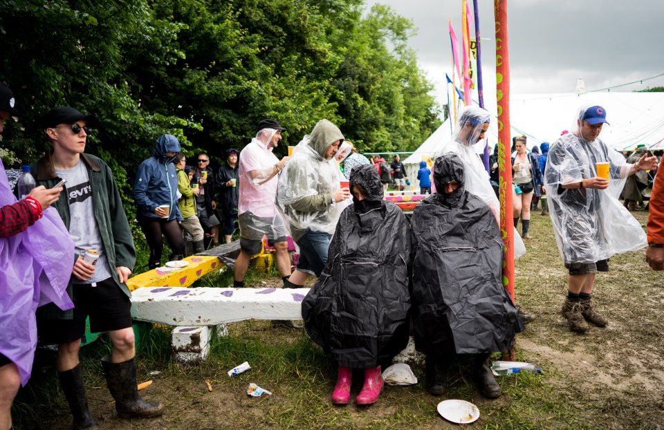  Two revellers take shelter from today's downpour by wrapping themselves in waterproof plastic sheets