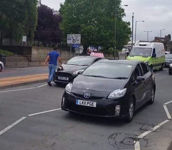  Minicab driver stands in front of a driving instructor car in an alleged road rage stand-off caught on video