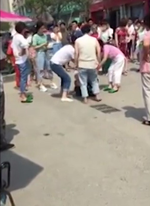  Even though a woman tries to step in and stop the attack, the group continues to beat the girl