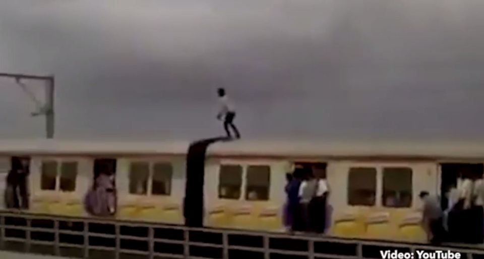  The footage begins with the man perched precariously on top of the train