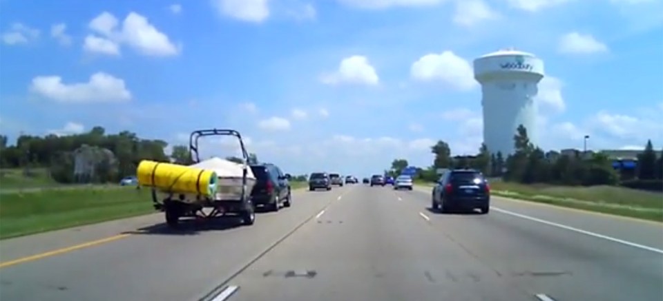  This video captures the dramatic moment a motorcyclist manages to narrowly escape death when a foam mat flies off the back of a black SUV and hits his bike.