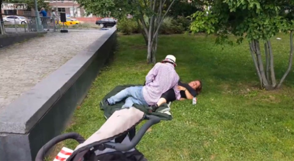  The couple start to lie down in an embrace in the busy park