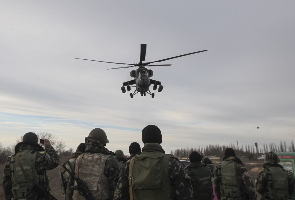 Russian army MI-35 military helicopter patrols the area as Ukrainian servicemen guard a checkpoint near the village of Strelkovo