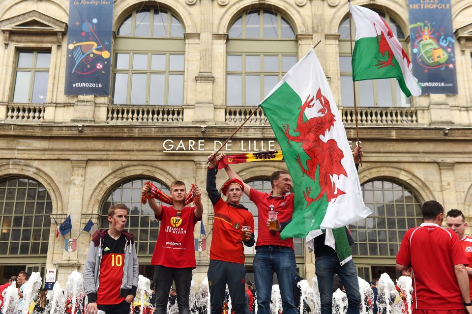  Belgian fans fly the Welsh flag as the rival supporters mixed happily outside the main railway station in Lille