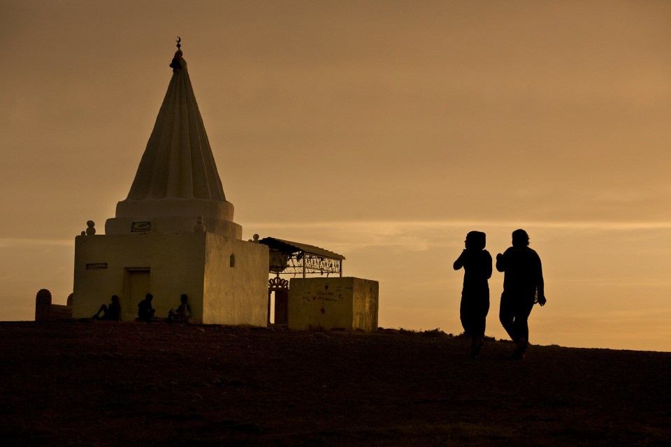 The sun sets as two women visit a shrine in a displacement camp for women in northern Iraq