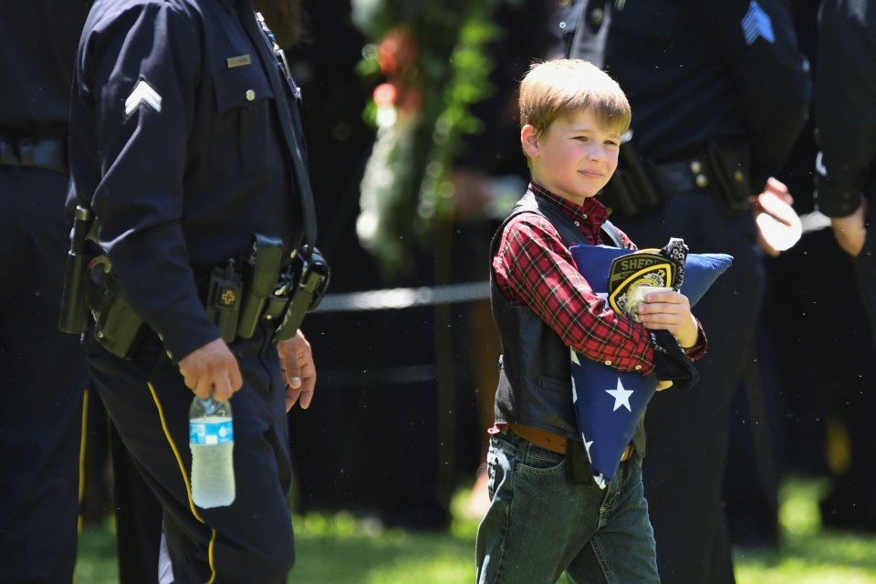  Magnus carries a folded U.S. flag after the burial of his hero dad