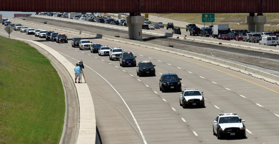  Police cars from different departments make up a funeral procession for slain officer