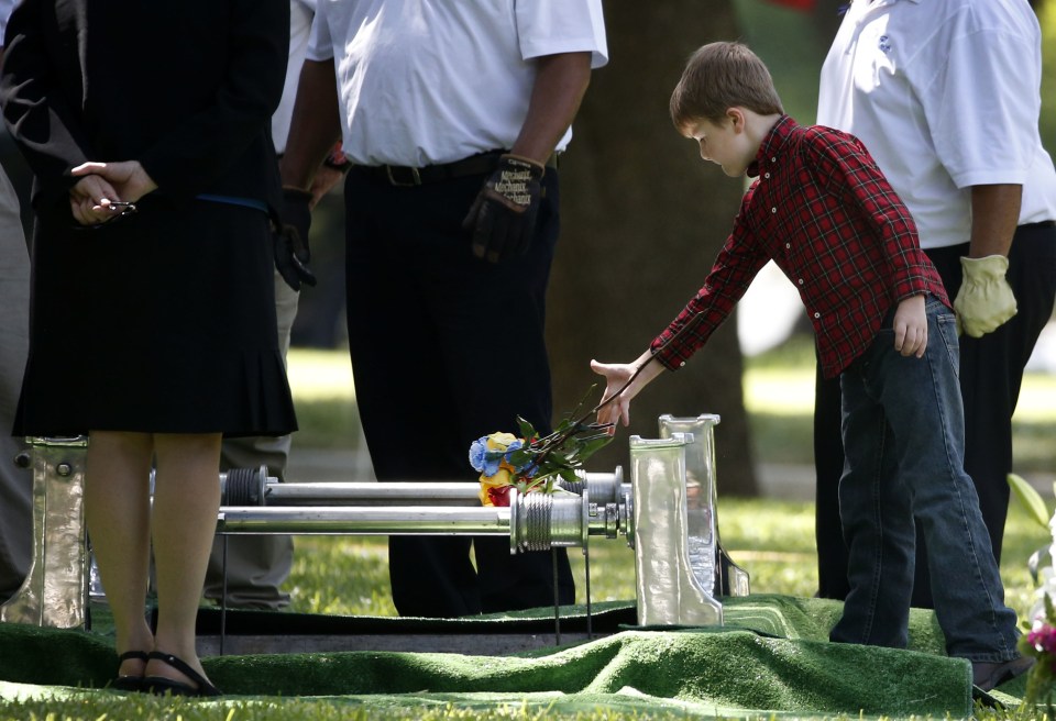  The 8-year-old throws some flowers on his father's casket