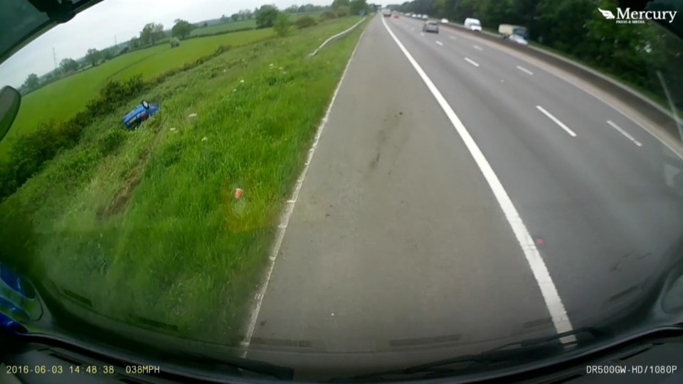  The Peugeot flies into a ditch and comes to rest on its roof beside the motorway