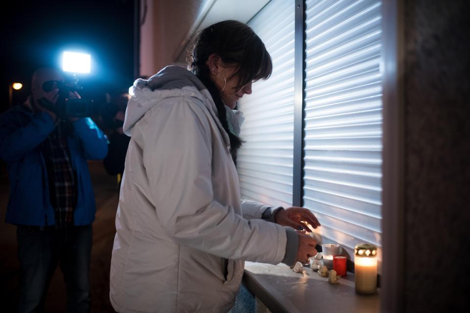 A woman lights a candle in tribute to the killing of the infants