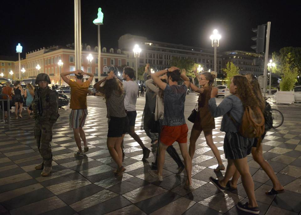 People crossed the street with their hands on their heads as French authorities secure the area