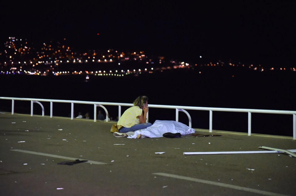  A devastated woman sits on the phone beside a covered-up body in Nice