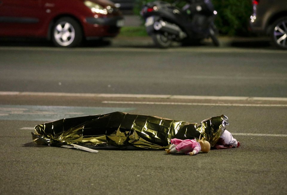  A body of a child, lying beside a doll, is covered following the attack in Nice