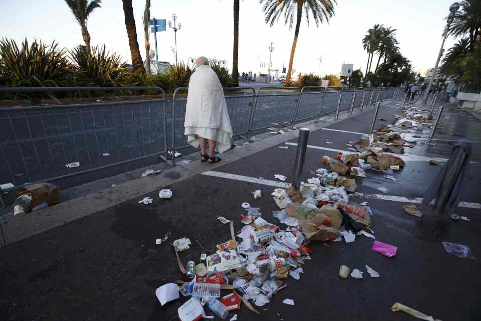  A man walks through debris scatterd on the street the day after a truck ran into a crowd at high speed killing scores celebrating the Bastille Day