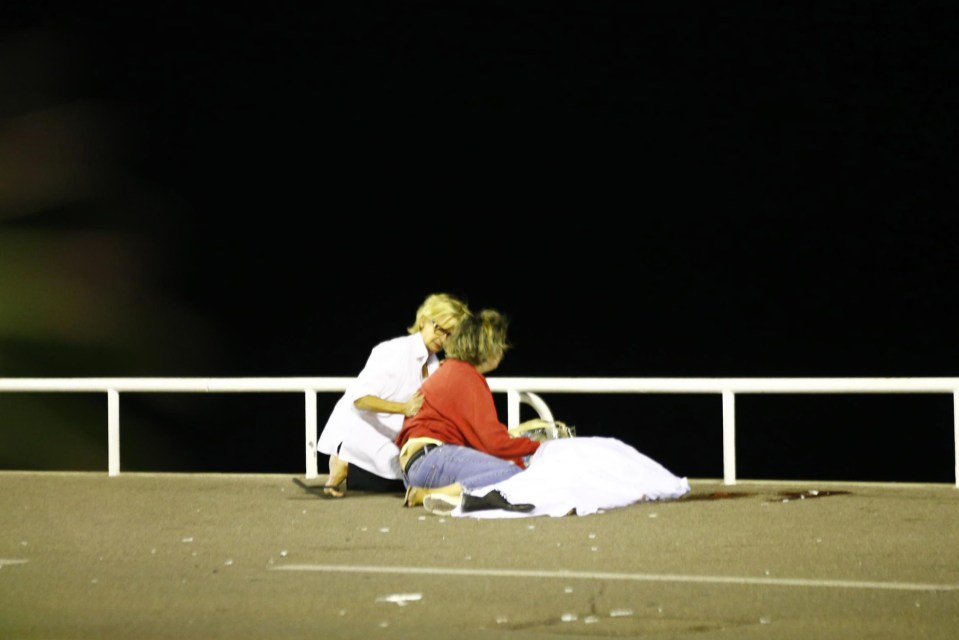  Survivors comfort each other beside a body close to the scene of the horror attack on a Nice promenade