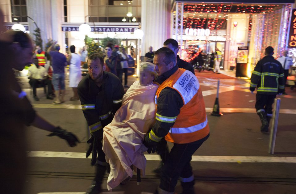  An injured woman is carried by paramedics in Nice after a lorry mounted the pavement and mowed people down