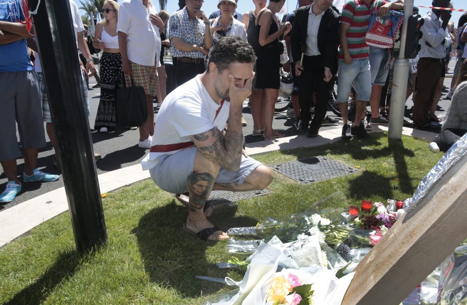  A devastated man mourns beside flowers left for the victims of the Nice attack